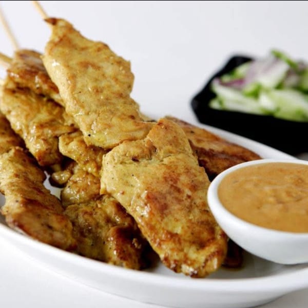 Thai chicken satay skewers with peanut sauce and a side of cucumber salad.